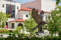 阳光明媚的日子里，校园大楼前的红鹰雕像.